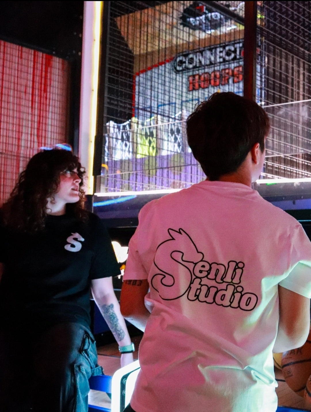 Modelo tirando a canasta con camiseta blanca de espaldas y modelo femenina con camiseta negra Basic T-Shirt de frente
